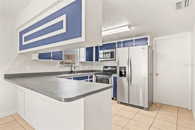 a kitchen with stainless steel appliances granite countertop a refrigerator a stove and a sink with wooden cabinets
