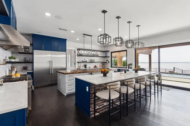 a kitchen with stainless steel appliances granite countertop a table chairs stove and wooden floor