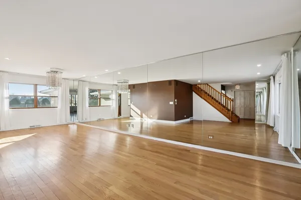 a kitchen with stainless steel appliances granite countertop a refrigerator a stove a sink a dining table and chairs with wooden floor
