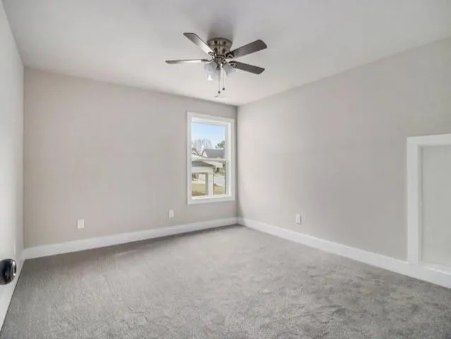 an empty room with a ceiling fan and window