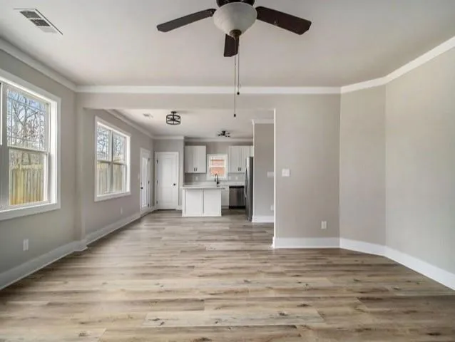 a view of an empty room with window and wooden floor