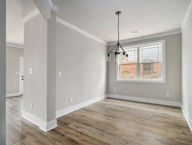 a view of empty room with wooden floor and window