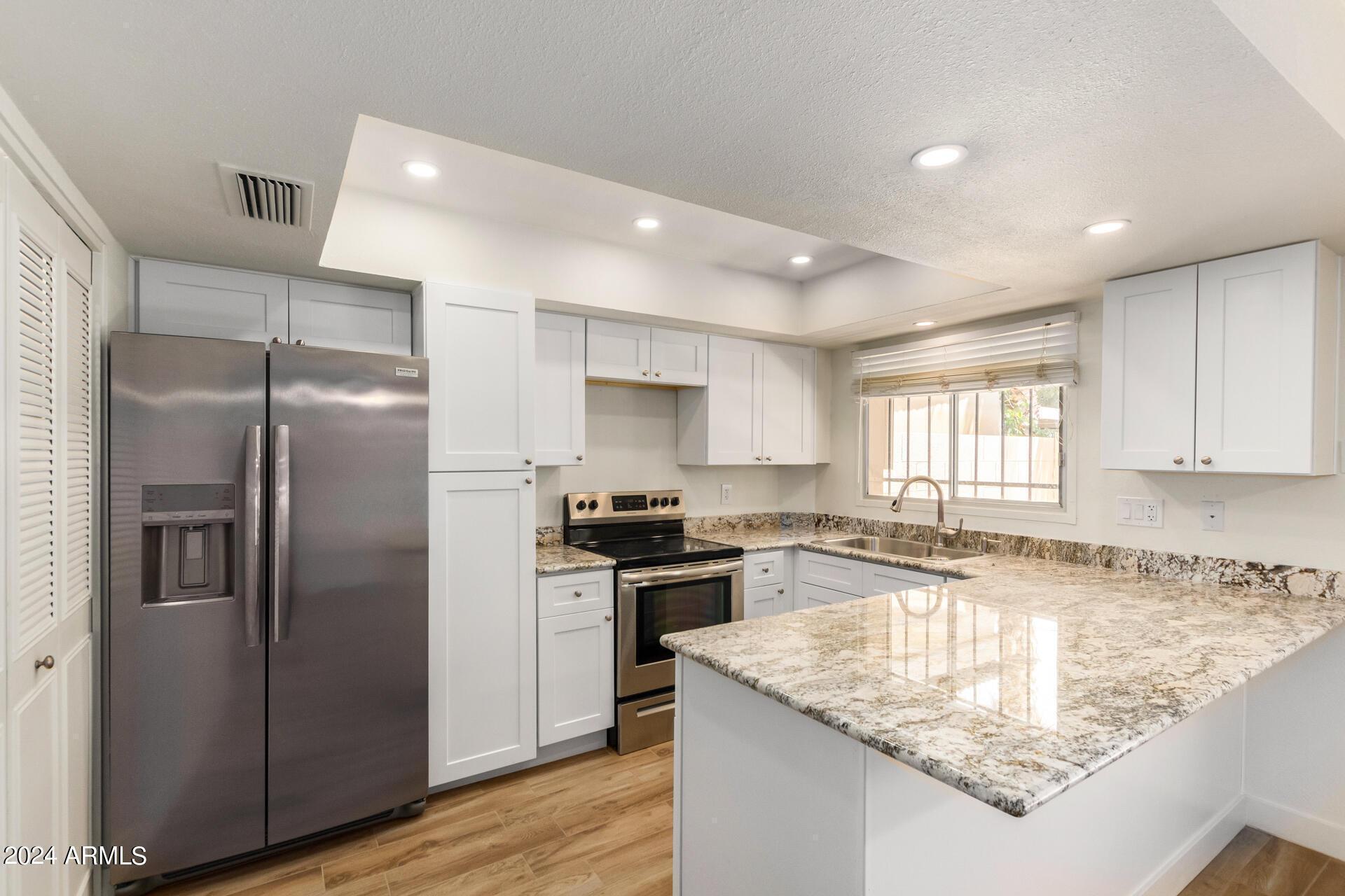 a kitchen with stainless steel appliances granite countertop a sink stove and refrigerator