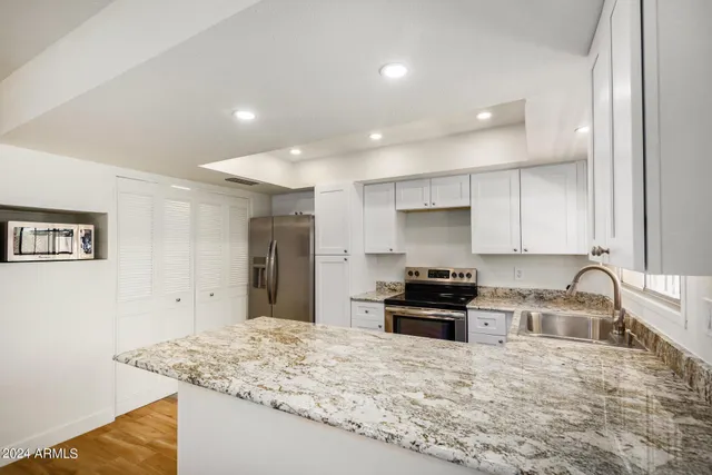 a kitchen with granite countertop a stove and a refrigerator
