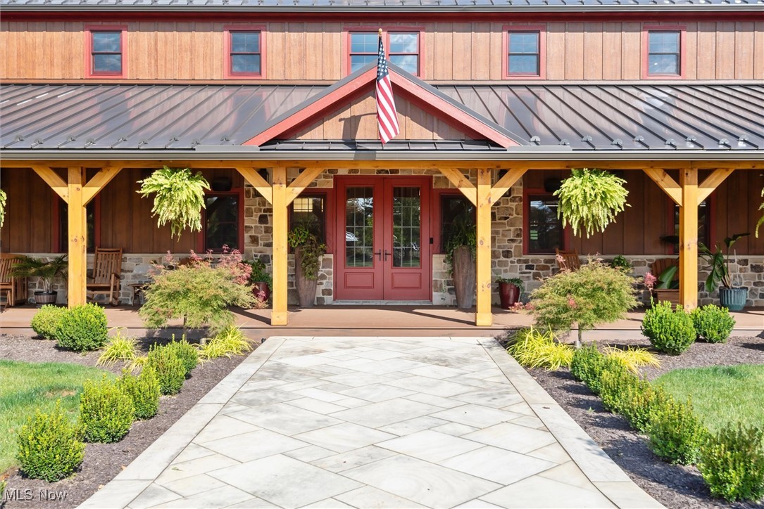 290 Townline Road Aurora, OH 44202 - Photo 4 of 50 Entrance to property featuring stone siding, a standing seam roof, a metal roof, a porch, and french doors