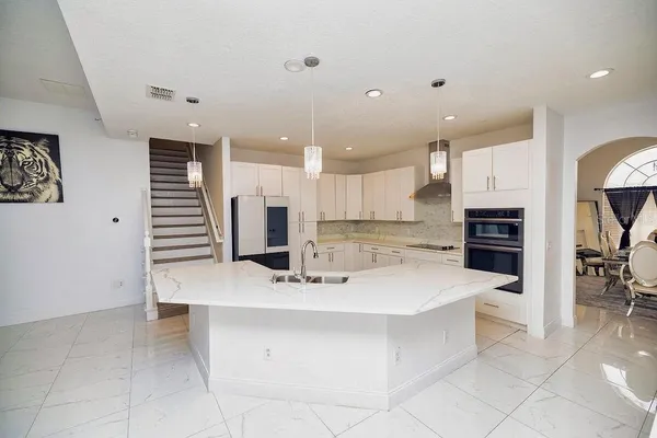 a large white kitchen with a sink stainless steel appliances and cabinets