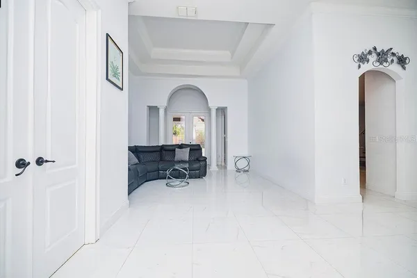 a living room with stainless steel appliances furniture a flat screen tv and a refrigerator