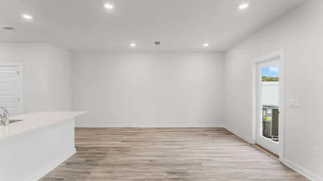 a view of an empty room with wooden floor and a sink