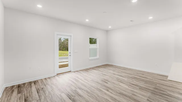 a view of an empty room with wooden floor and a window