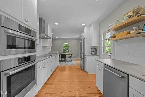 a large kitchen with stainless steel appliances kitchen island a large counter top a stove a chimney a sink and a refrigerator