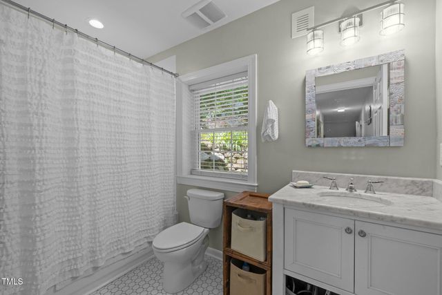 a bathroom with a toilet a sink a mirror a window and vanity