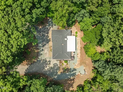 an aerial view of a house with a yard and large trees