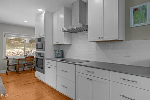 a kitchen with white cabinets and window