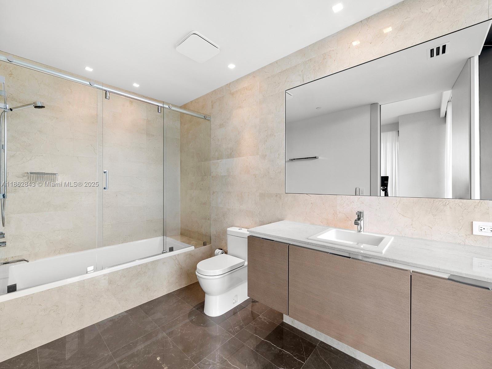 19575 Collins Avenue, Unit 9 Sunny Isles Beach, FL 33160 - Photo 54 of 91 a bathroom with a granite countertop sink a toilet a mirror and bathtub