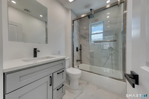 a bathroom with a shower sink vanity mirror and toilet
