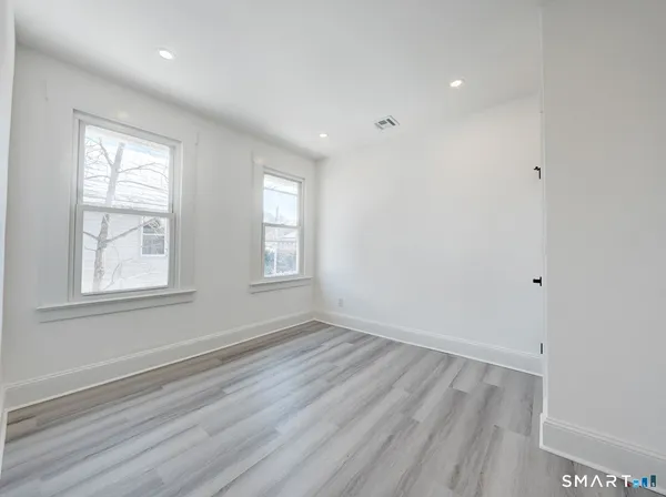 an empty room with wooden floor and windows