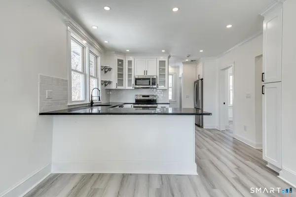 a view of a kitchen with stainless steel appliances wooden floor and a window