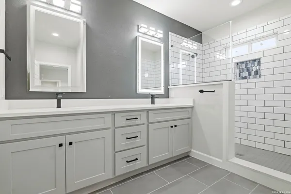 a bathroom with a double sink shower and a mirror
