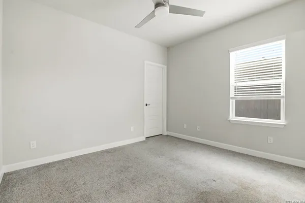 an empty room with a window and ceiling fan