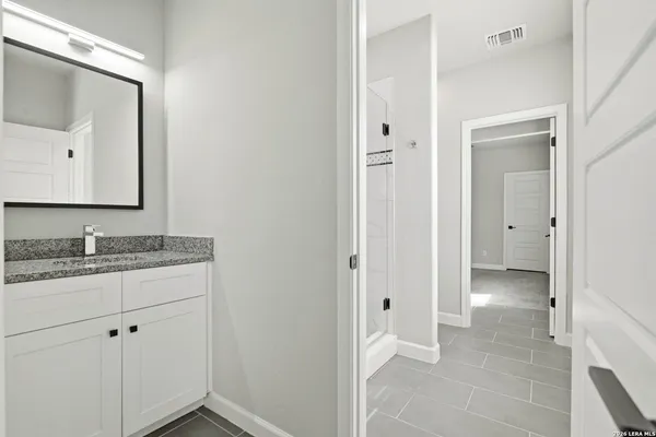 a bathroom with a granite countertop sink and a mirror