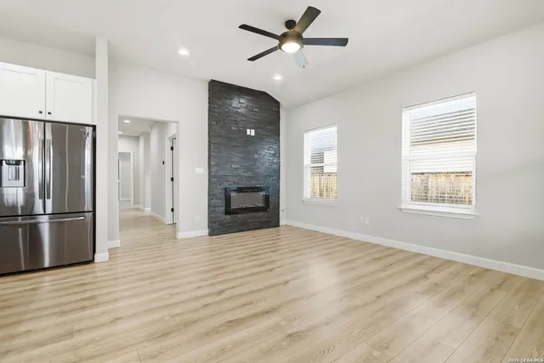 a view of a kitchen with a stove a refrigerator a ceiling fan and wooden floor