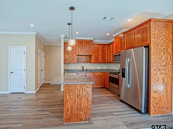 a kitchen with stainless steel appliances granite countertop a refrigerator a sink dishwasher a stove and a refrigerator with wooden floor
