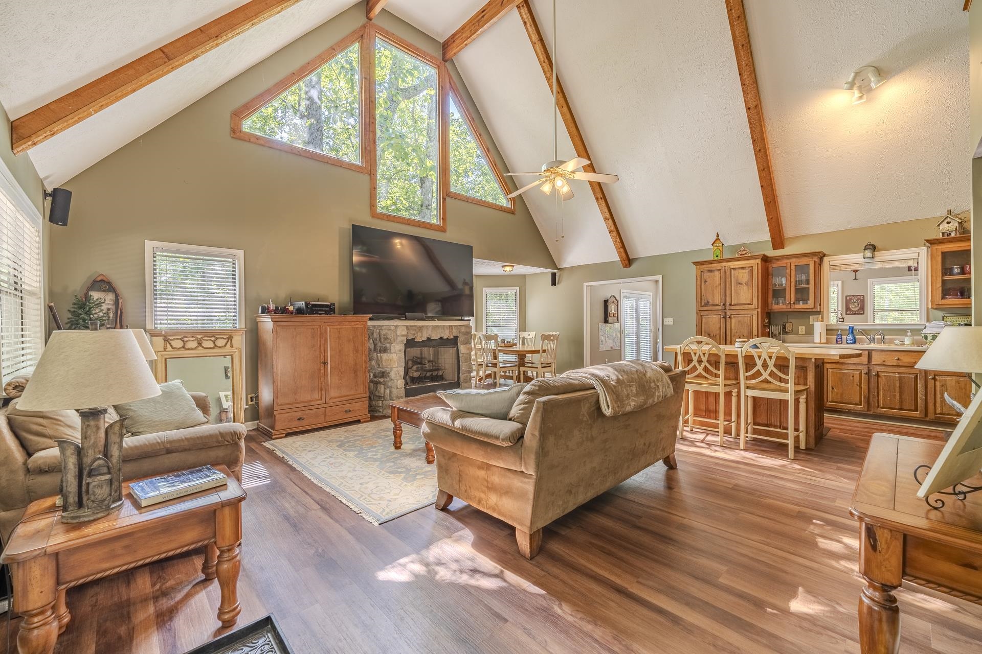 435 Murray Lane Counce, TN 38326 - Photo 7 of 34 Vaulted ceiling living area featuring exposed wood beams, a stone fireplace, and wood-finish flooring