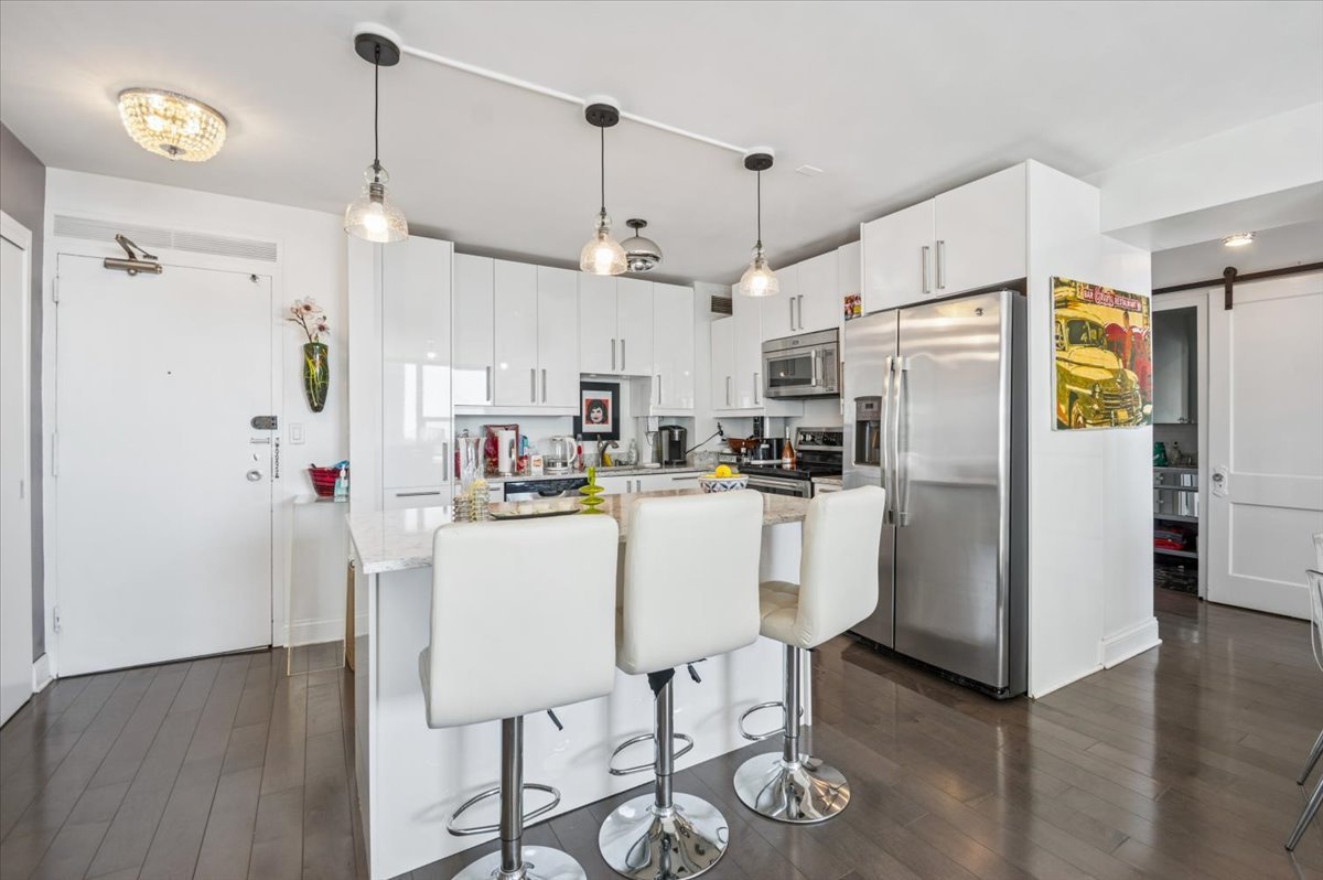3600 North Lake Shore Drive, Unit 1601 Chicago, IL 60613 - Photo 5 of 16 a kitchen with stainless steel appliances kitchen island a refrigerator a stove and white cabinets with wooden floor