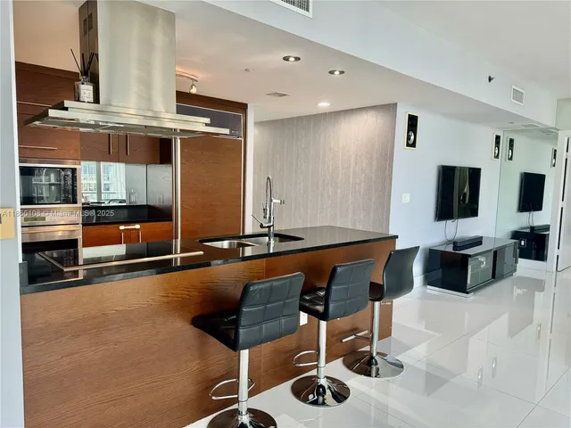 a living room with furniture a flat screen tv and kitchen view