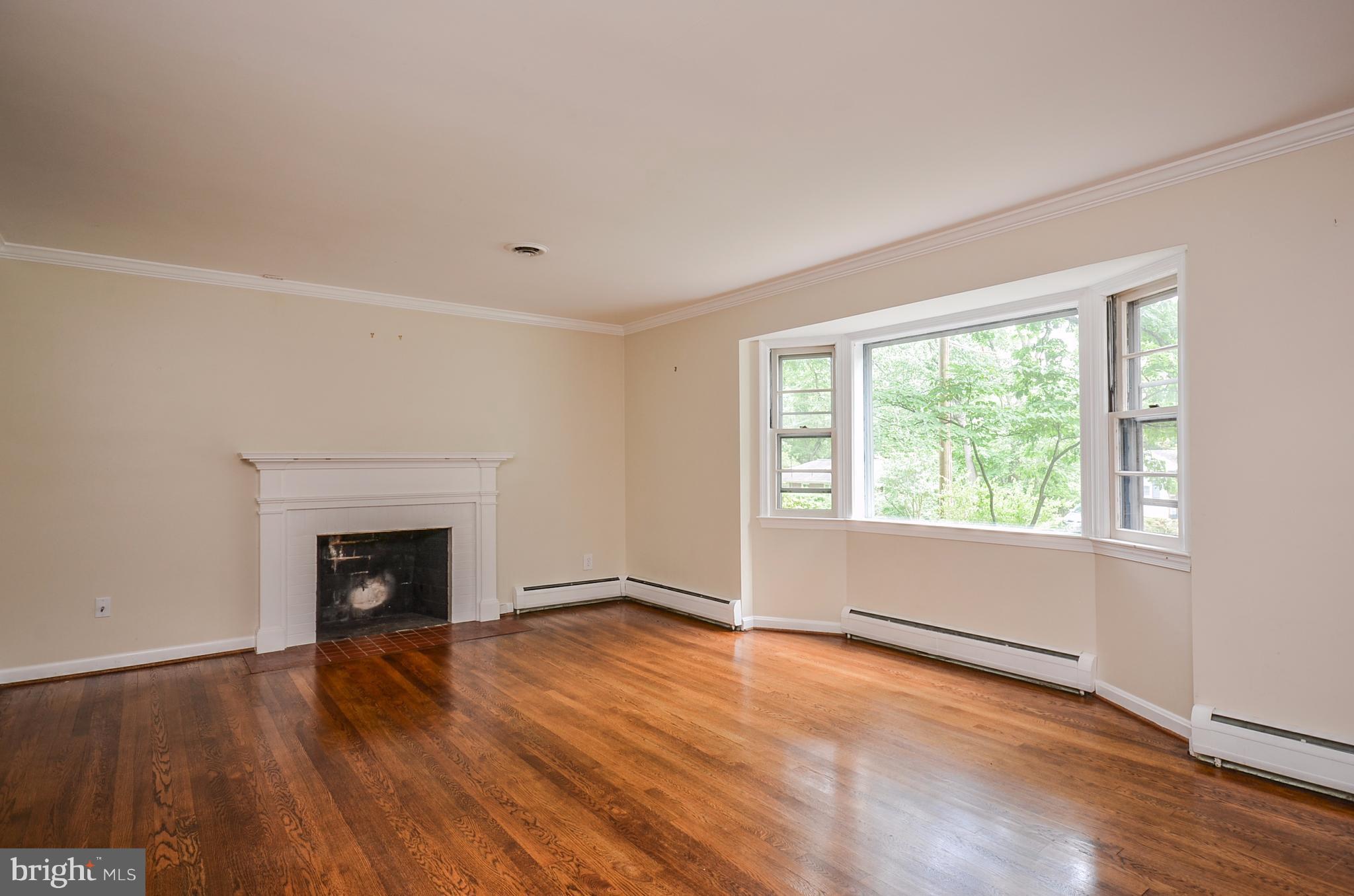10751 Kinloch Road Silver Spring, MD 20903 - Photo 3 of 30 an empty room with wooden floor fireplace and windows
