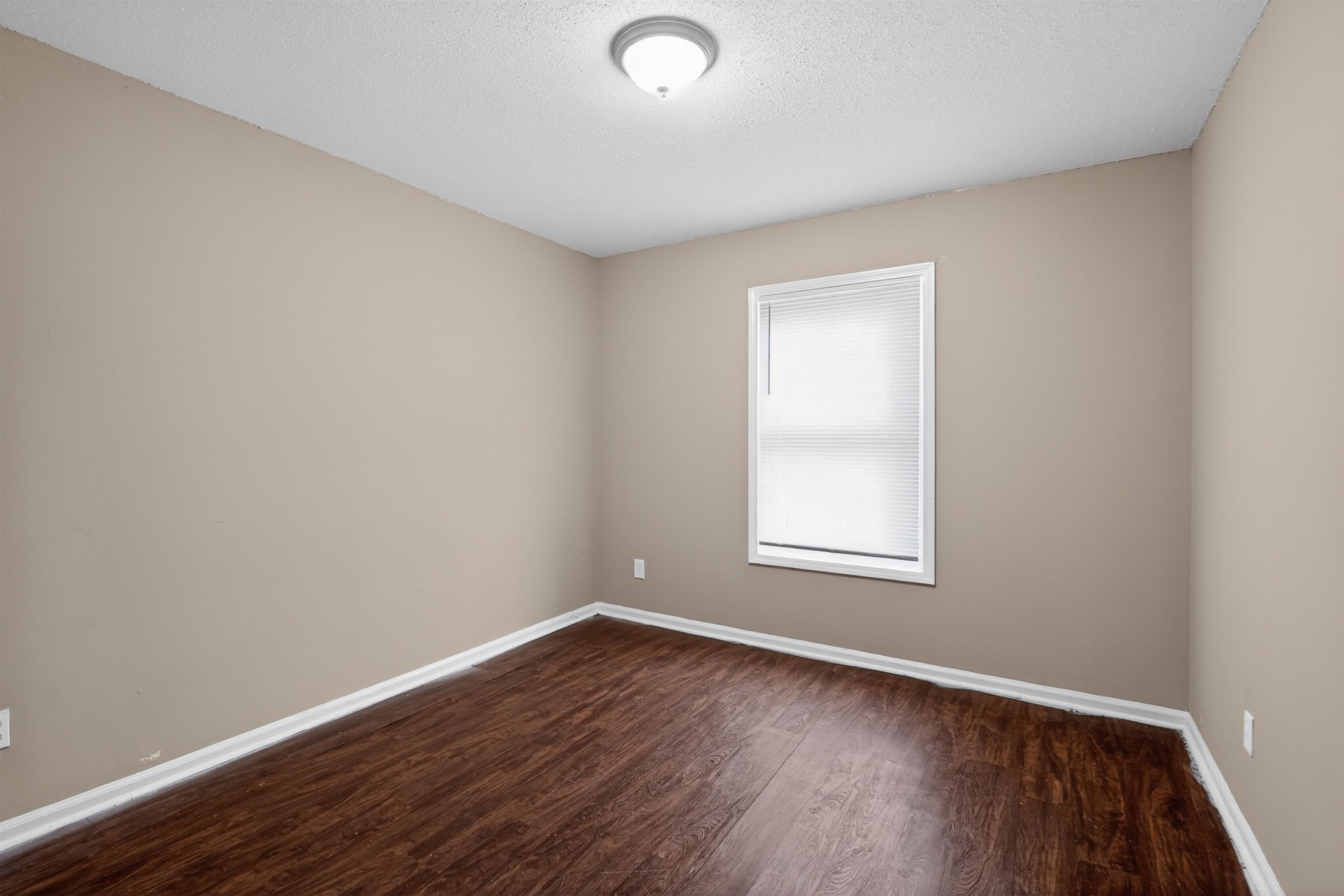 3608 Cane Ridge Drive Memphis, TN 38109 - Photo 16 of 31 Room featuring wood-finish flooring, neutral wall tones, white baseboards, and a window with blinds