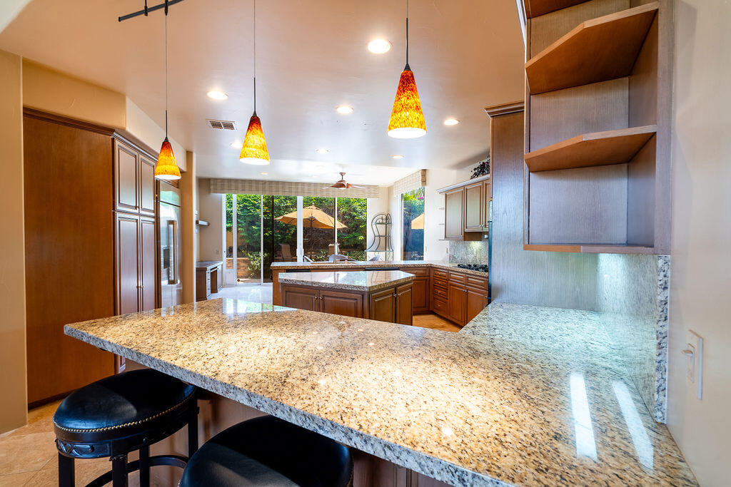 79160 Jack Rabbit Trail La Quinta, CA 92253 - Photo 36 of 48 a kitchen with stainless steel appliances kitchen island granite countertop a table chairs in it and wooden floors