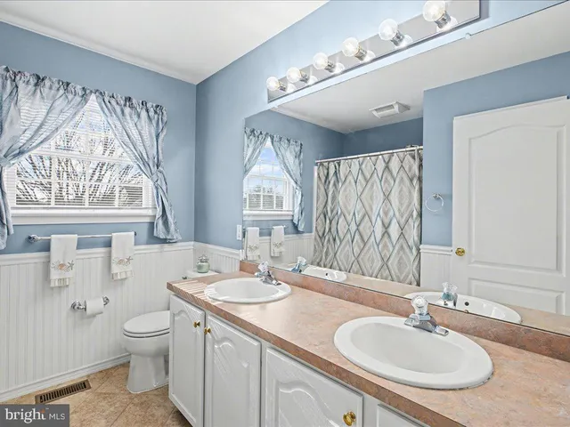 a bathroom with a granite countertop double vanity sink a mirror and a toilet