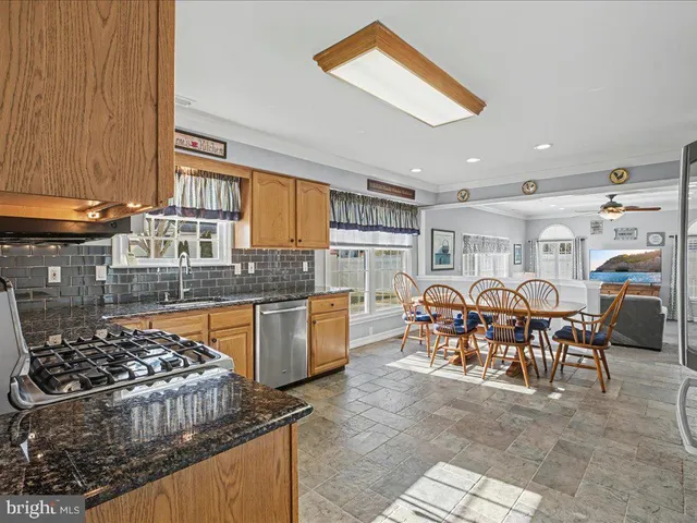 a kitchen with stainless steel appliances granite countertop a stove top oven a sink a dining table and chairs with the view of kitchen