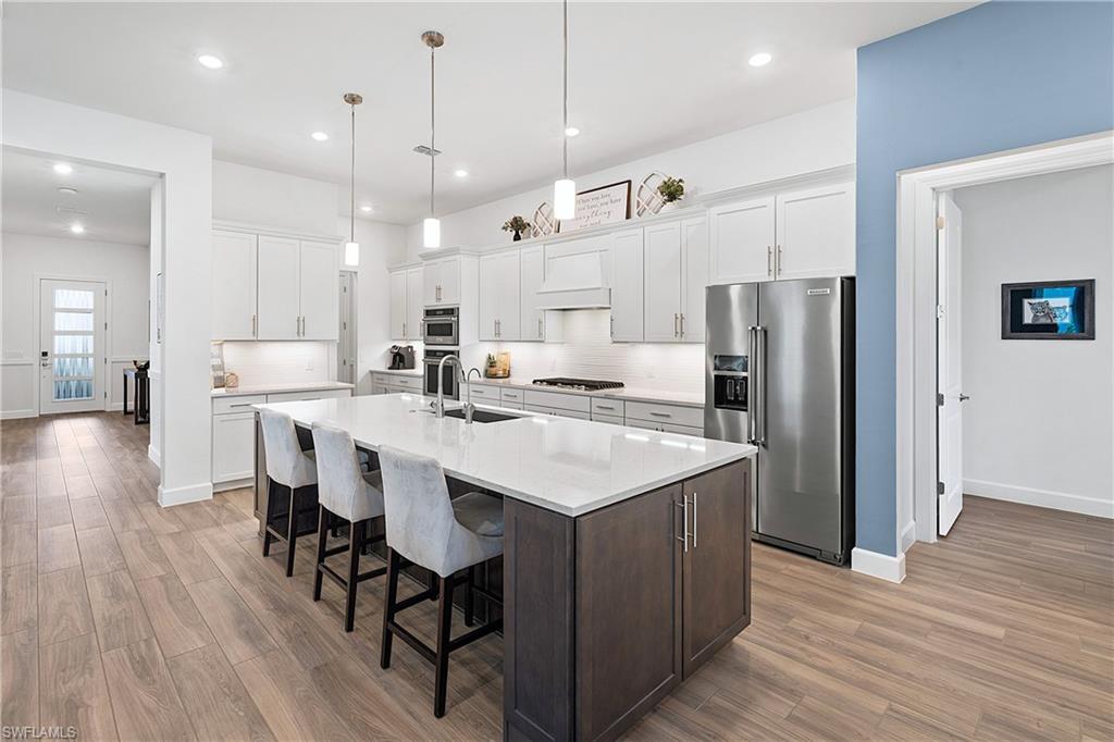 20549 Napa Loop Estero, FL 33928 - Photo 29 of 50 a kitchen with kitchen island white cabinets and stainless steel appliances
