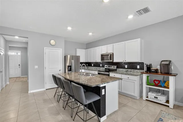 a kitchen with stainless steel appliances granite countertop a sink refrigerator and cabinets
