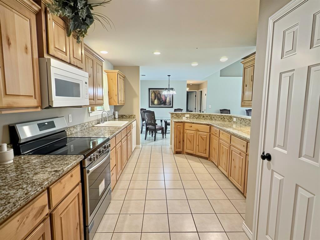 313 East River Oaks Road Early, TX 76802 - Photo 9 of 34 Kitchen featuring wood-finish cabinetry, light-toned countertop, stainless steel appliances, and a tile floor