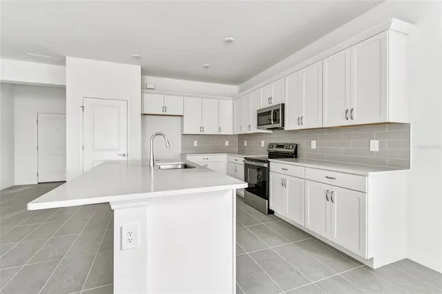 a kitchen with granite countertop a sink stove and white cabinets