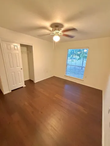 an empty room with windows and fan