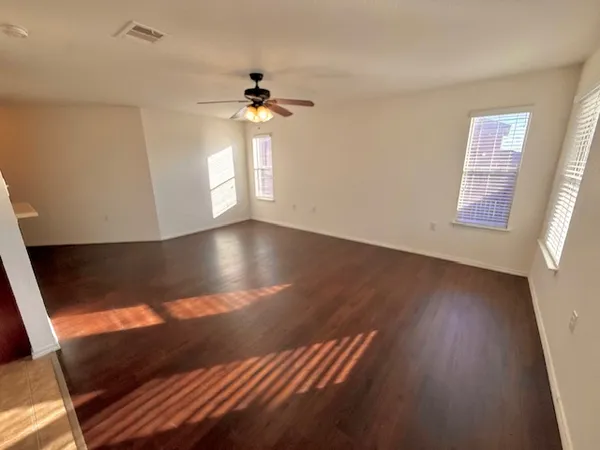 a view of an empty room with wooden floor and a window