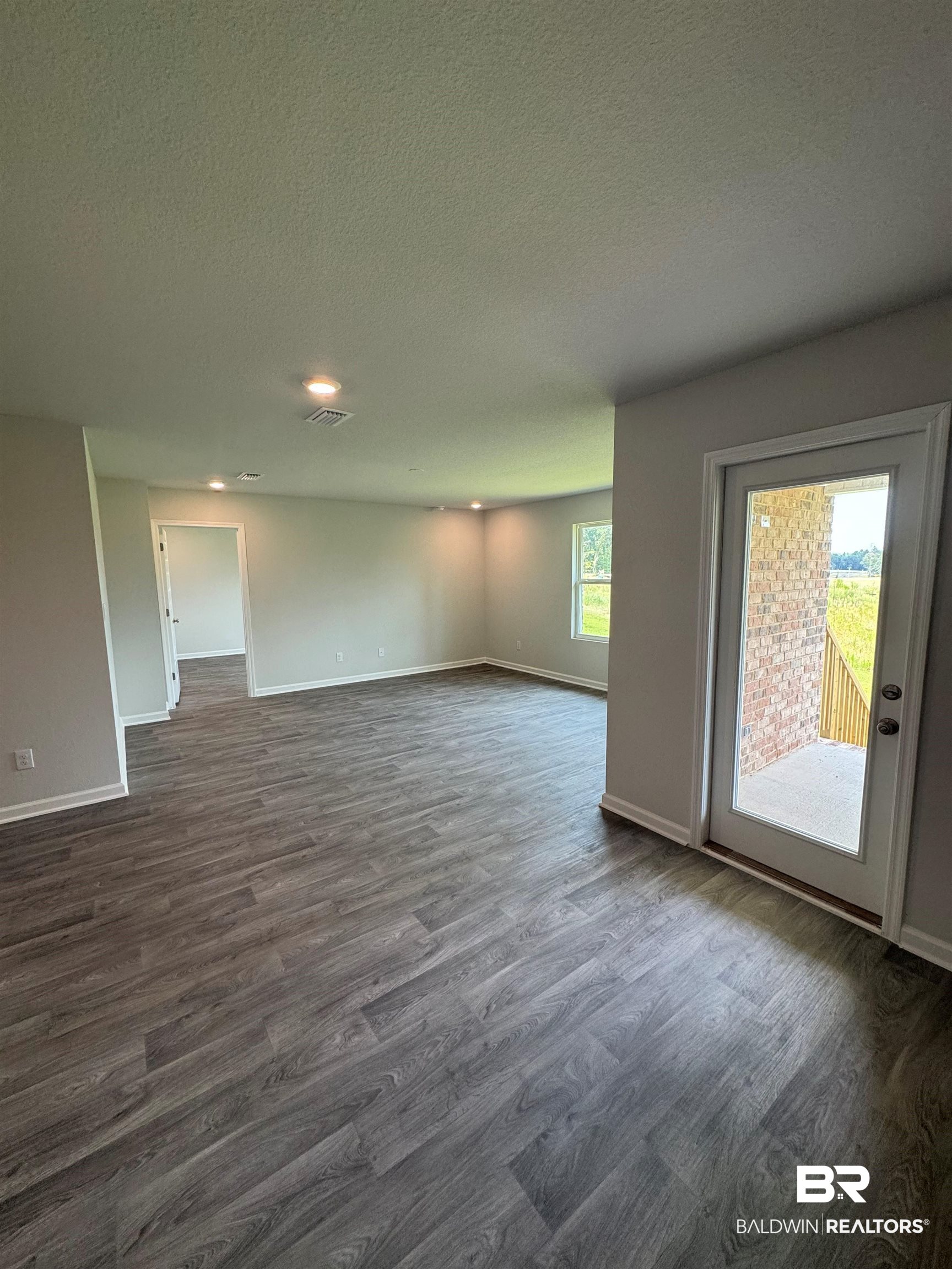 11335 Elemis Drive Daphne, AL 36526 - Photo 9 of 11 Unfurnished room featuring hardwood / wood-style floors, a textured ceiling, and a healthy amount of sunlight