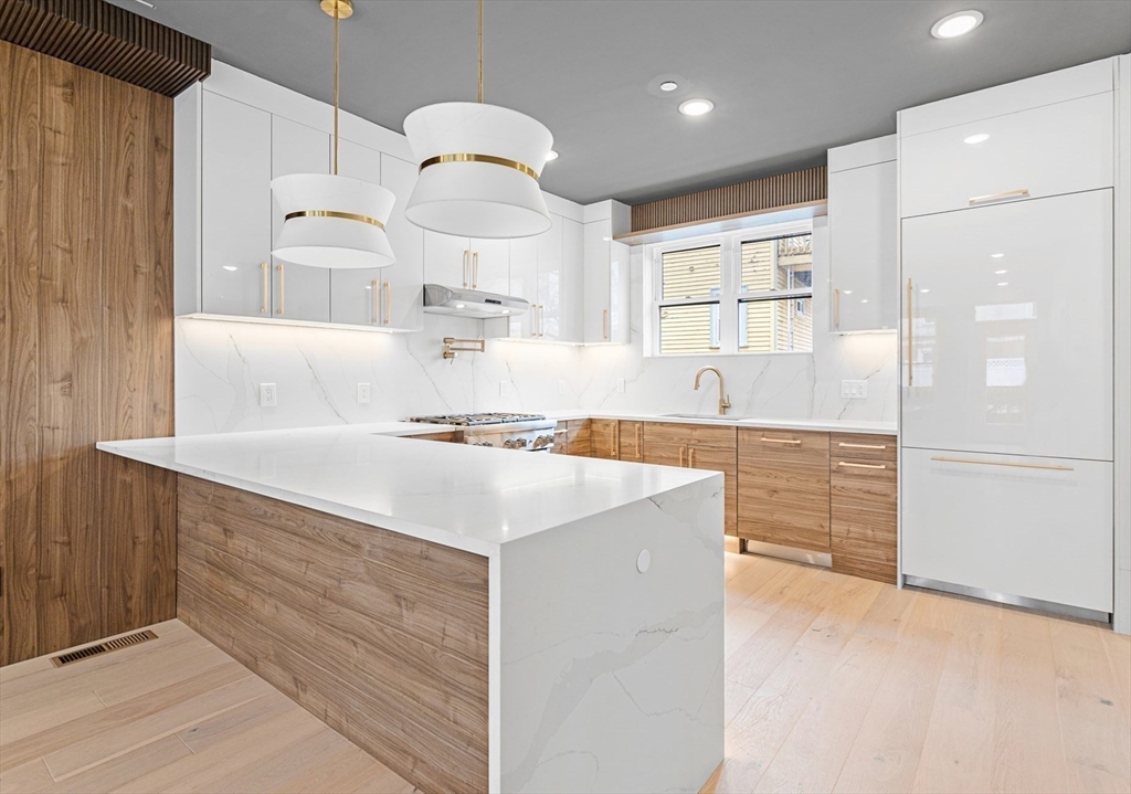 a kitchen with kitchen island a sink a stove a refrigerator and white cabinets