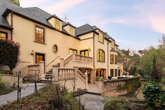 a view of a big house with a big yard plants and large trees
