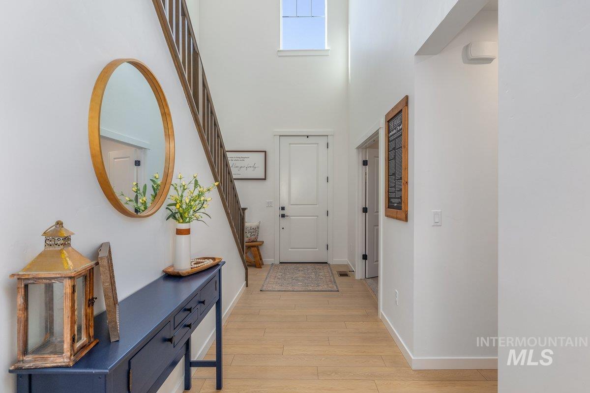 1380 West Chilitna Street Meridian, ID 83642 - Photo 5 of 50 Entryway featuring wood-finish flooring, a double-height ceiling, a window at upper level, a white paneled door, and a wooden staircase with dark risers