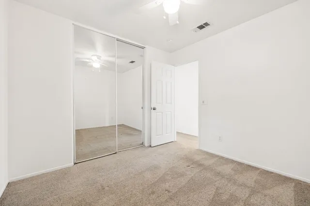 an empty room with a chandelier fan and windows
