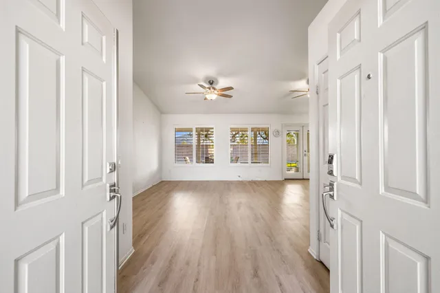 a view of an empty room with a window and wooden floor