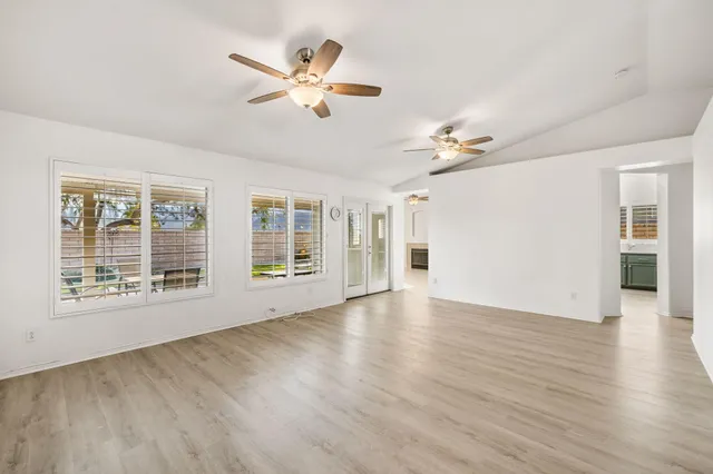 a view of an empty room with a window and wooden floor