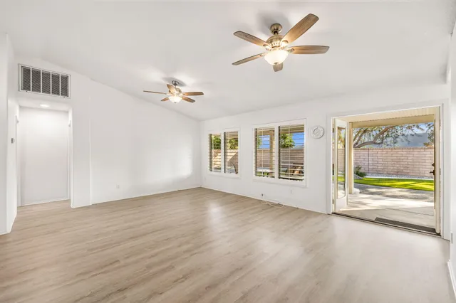 a view of an empty room with a window and a ceiling fan