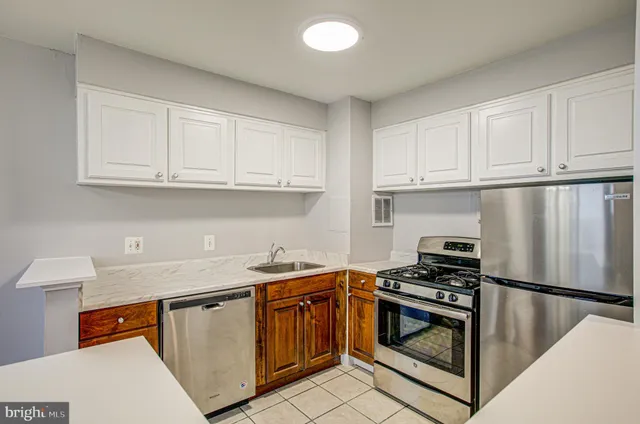 a kitchen with stainless steel appliances granite countertop a stove a refrigerator and a sink with white cabinets