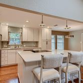 a kitchen with stainless steel appliances kitchen island granite countertop a dining table chairs refrigerator and sink